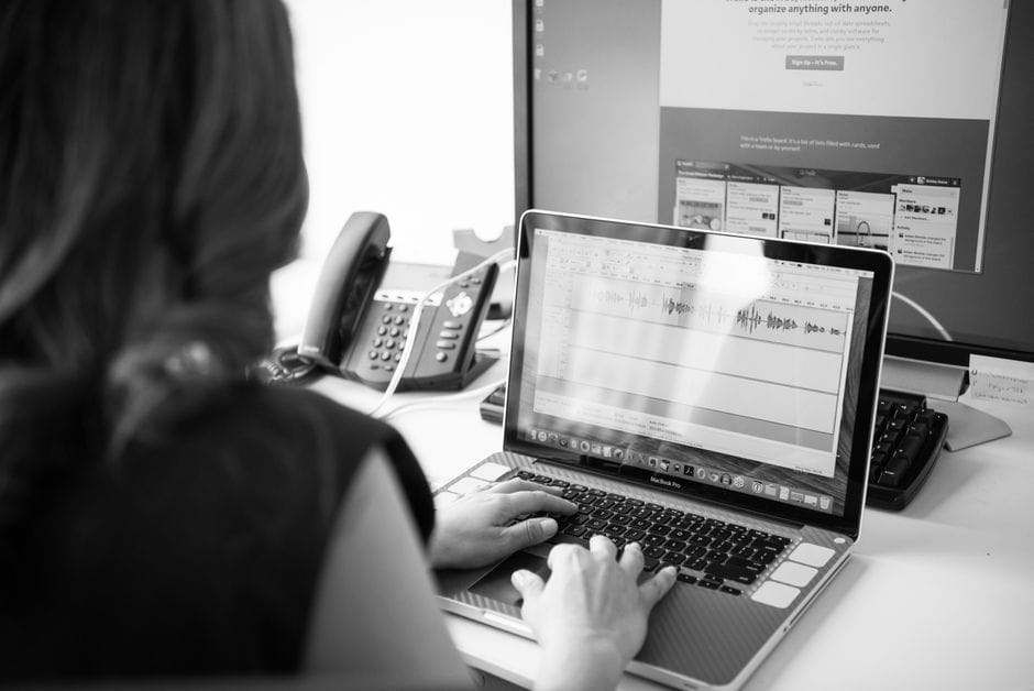 How to Merge, Reorder, and Organize PDF Files (Complete Guide) Black and white office scene with a woman working on a laptop in front of dual monitors.