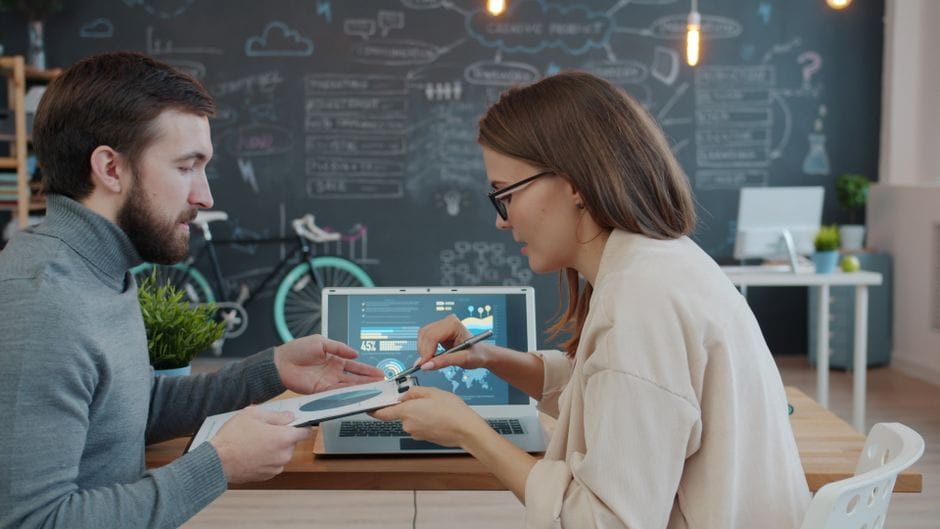 Two professionals collaborating at a modern office with a chalkboard wall.