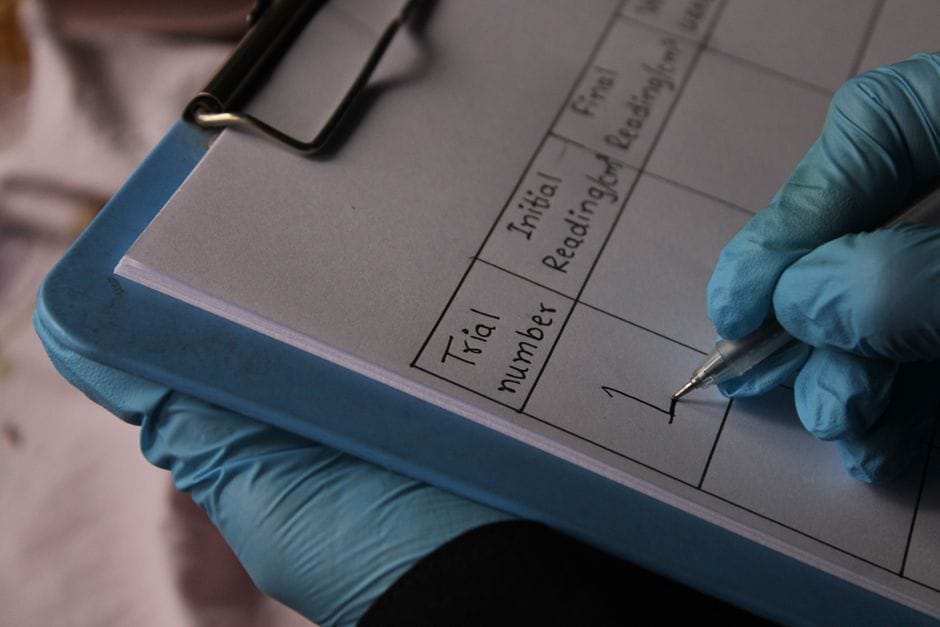 How to Remove a Watermark from a PDF Close-up of a gloved hand writing in a lab notebook, documenting trial readings.
