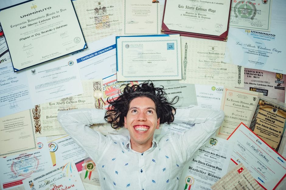 How to Compress a PDF for a Job Application Upload Happy man lying among numerous certificates and diplomas celebrating achievements.