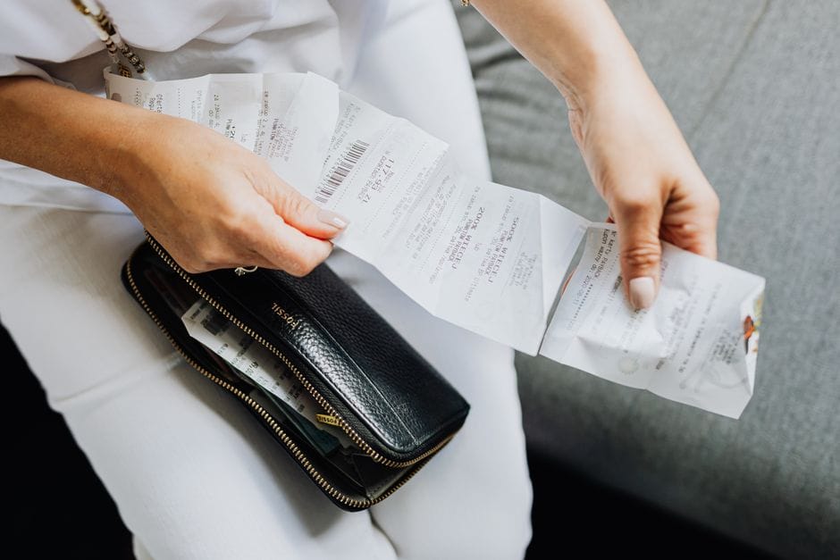 How to Convert Multiple JPG Images Into One PDF Close-up of a woman's hands managing multiple receipts taken from a black wallet.