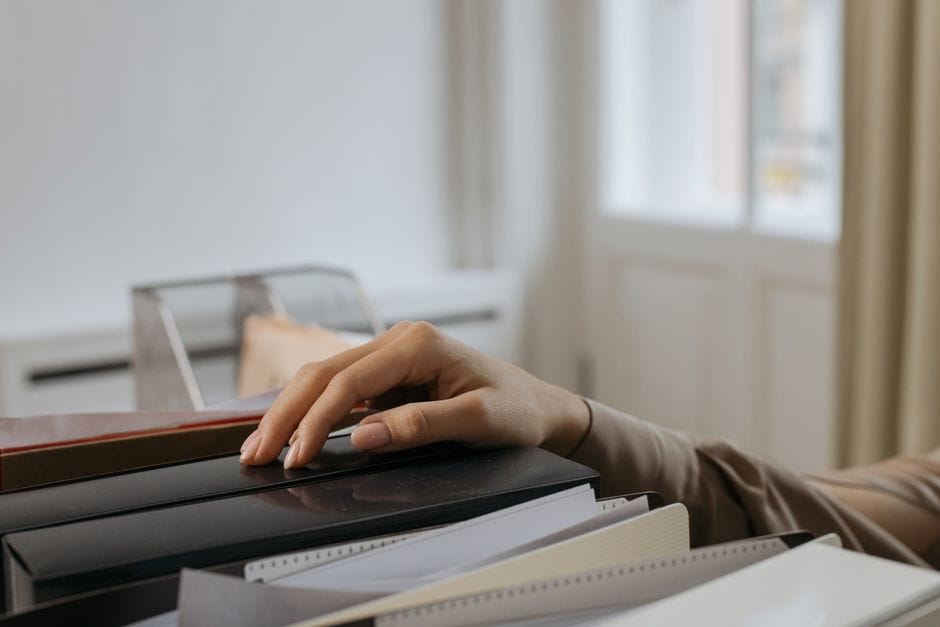 How to Remove Blank and Unwanted Pages From a Scanned PDF An adult's hand reaches for office file folders, capturing a thoughtful moment. Indoors setting.