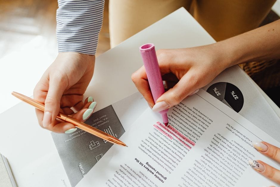 Hands highlighting and taking notes on a document with pen and highlighter.