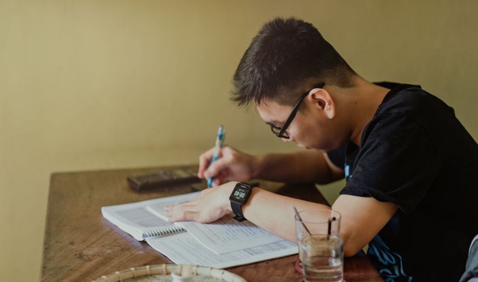 A PDF Workflow for Students: Assignments, Thesis Chapters, and Submissions A young man concentrates on studying at his desk, taking notes indoors.