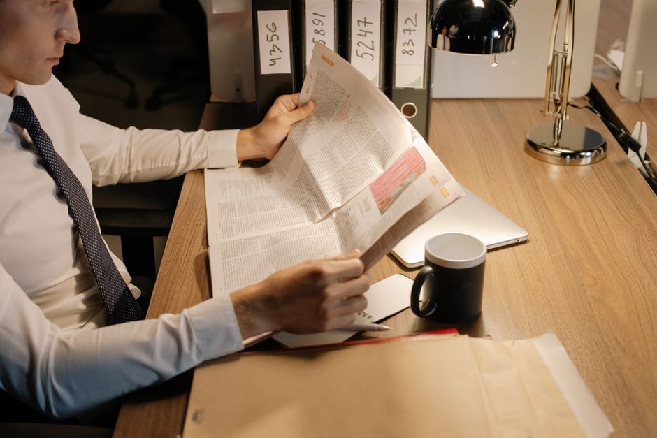 How to Rotate PDF Pages Permanently (Not Just in Your Viewer) A focused businessman reads a newspaper at a wooden desk in his office, emphasizing work and information.