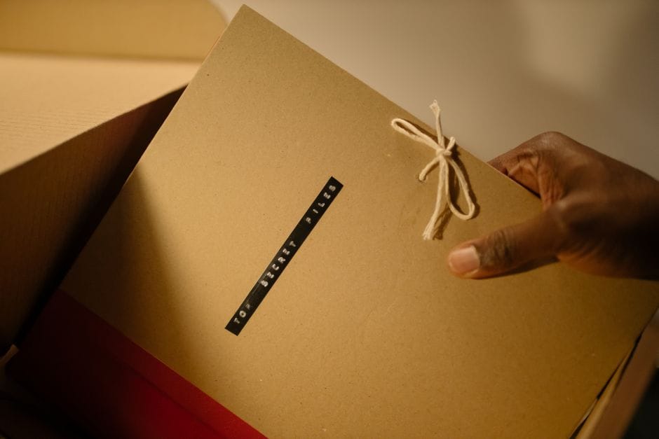 Cover vs Redact: Why a Black Box on a PDF Does Not Hide Anything Close-up of hand holding top secret document folder in a box.