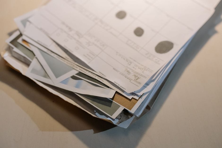 How to Fix a Sideways or Upside-Down Scanned PDF Close-up view of a stack of various papers and documents on a desk surface.