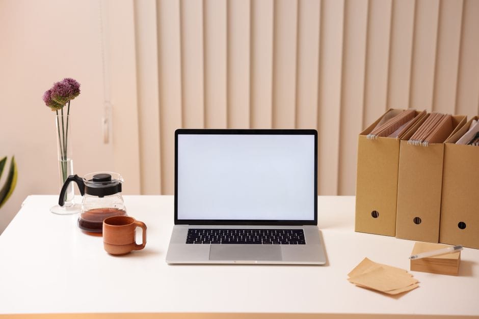 A minimalist workspace featuring a laptop, folder organizers, and coffee, ideal for productivity.