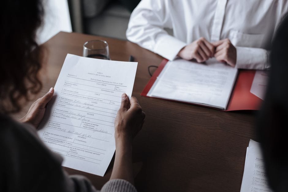 How to Merge Two PDF Files Into One for Free Two individuals discussing documents during a business meeting indoors.
